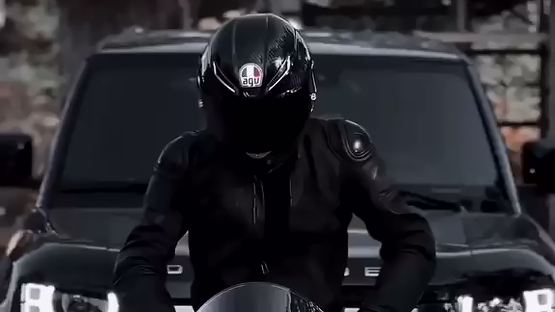 Siyah motosiklet üzerinde kasklı sürücü ve arkada siyah arazi aracı — Sadık Bal